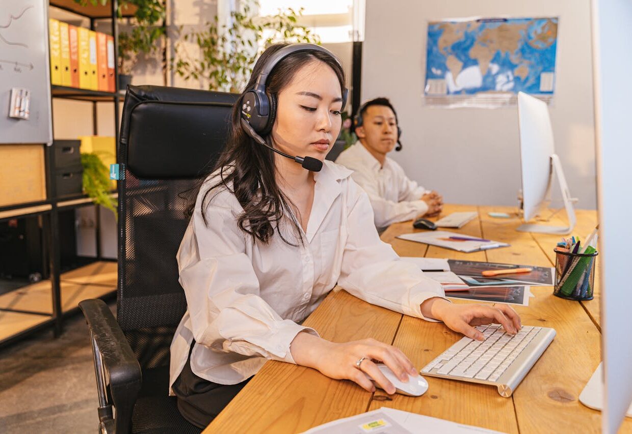 Two call center employees working on computers, focused and efficient, in a modern office setting.